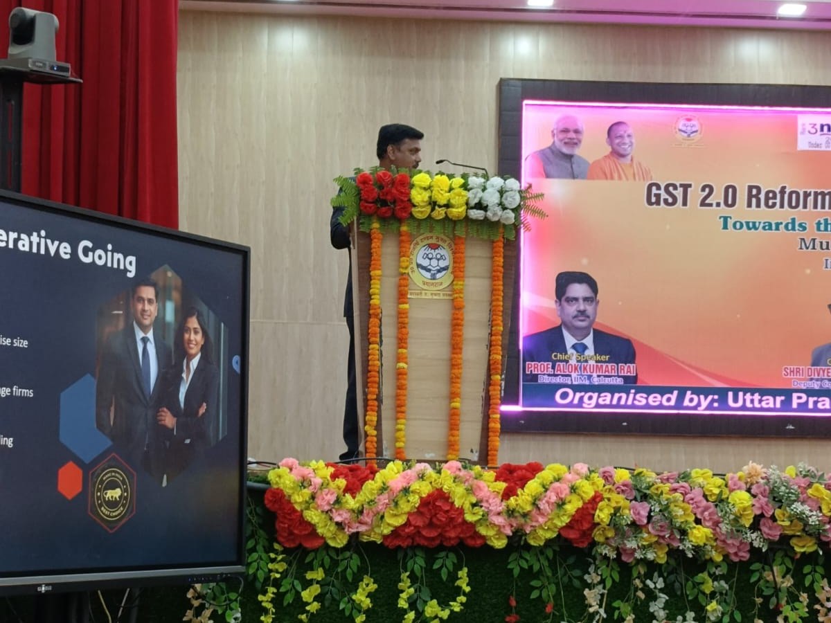 Rahul Chatterjee speaking at the podium at the U.P. Rajarshi Tandon Open University national seminar on GST 2.0 reforms, Viksit Bharat@2047 backdrop